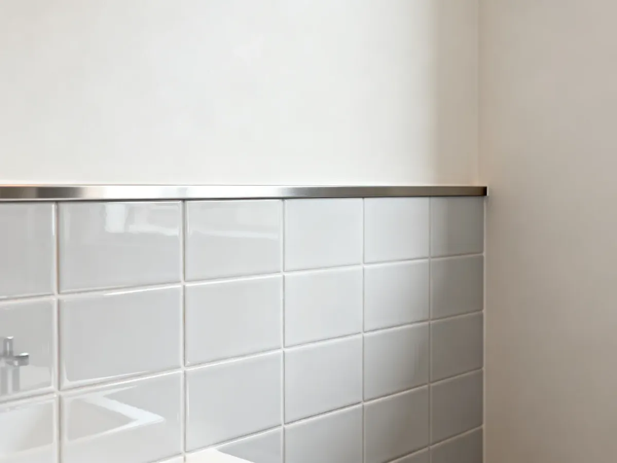 Górna krawędź płytek do połowy ściany wykończona metalowym profilem